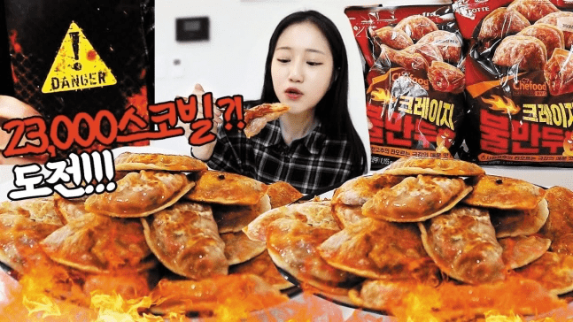 YouTuber "Maebhani" is eating Hell Fire Dumplings with a Scoville rating of 23,000 SHU. Focusing on spicy food mukbangs, their subscriber count has surged since last year, reaching around 300,000. Despite claiming not to find the food spicy, the channel's producer often suffers from trying to keep up.